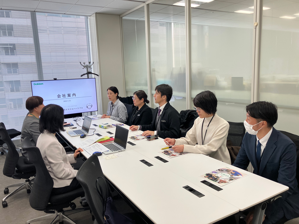 着席した状態で、沖縄県立特別支援学校の先生方が、投影資料をもとに会社概要の説明をうけています。