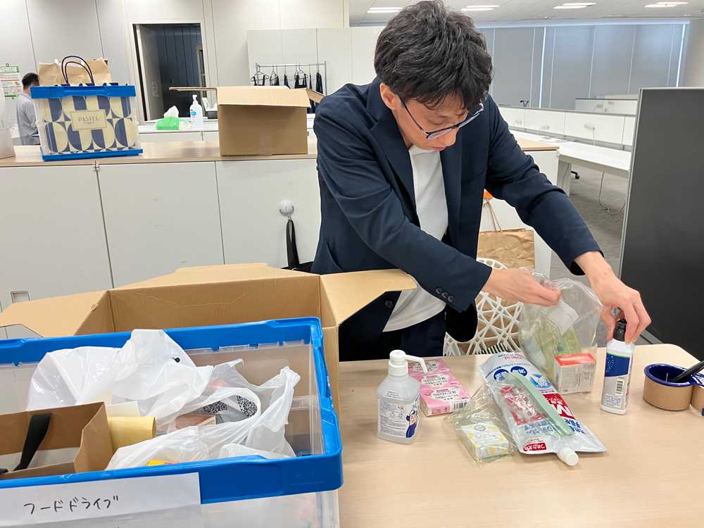 社員がフードドライブで集まった食品と日用品を仕分け・発送準備をしている様子です。